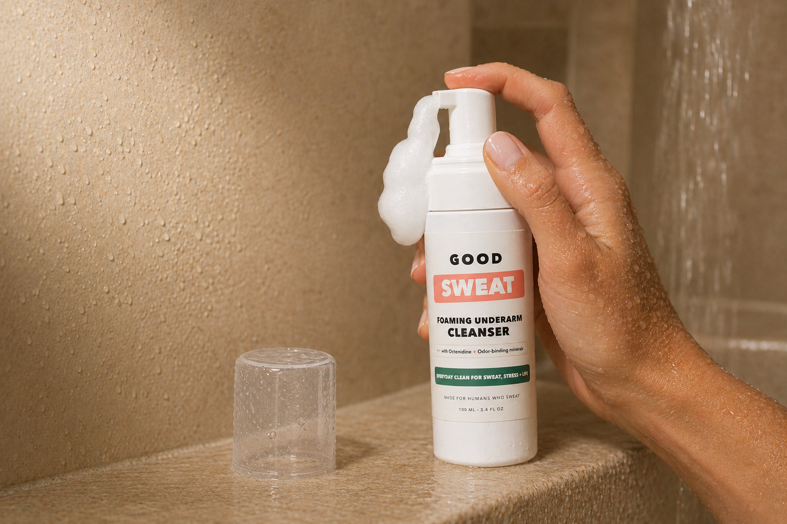 GoodSweat cleanser bottle dispensing foam in a shower.